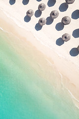 Image showing Aerial view of amazing tropical white sandy beach with palm leaves umbrellas and turquoise sea.