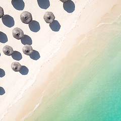 Image showing Aerial view of amazing tropical white sandy beach with palm leaves umbrellas and turquoise sea.