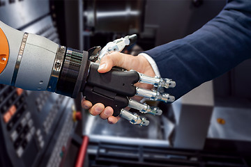 Image showing Hand of a businessman shaking hands with a Android robot.