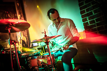 Image showing Drummer playing on drum set on stage.