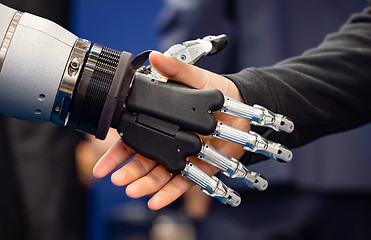 Image showing Hand of a businessman shaking hands with a Android robot.