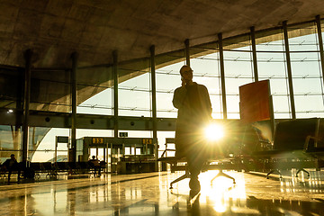 Image showing Female traveler talking on her cell phone while waiting to board a plane at departure gates at airport terminal.