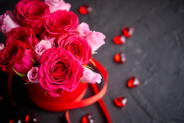 Image showing Pink roses bouquet packed in red box and placed on black stone background