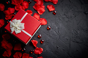 Image showing Gift box on black stone table. Romantic holiday background with rose petals