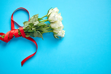 Image showing Bouquet of white roses with red bow on blue background