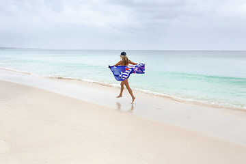 Image showing Female in motion with Australian flag running along the beach