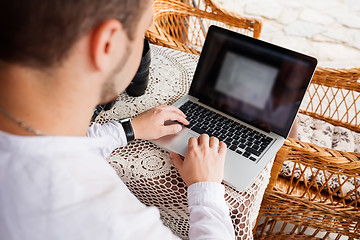 Image showing man working with laptop computer and sitting on sofa