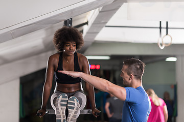 Image showing black woman doing parallel bars Exercise with trainer