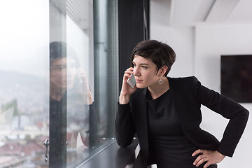 Image showing Elegant Woman Using Mobile Phone by window in office building