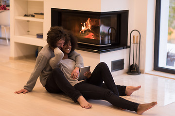 Image showing multiethnic couple using tablet computer on the floor