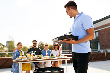 Image showing man cooking on bbq and friends at rooftop party