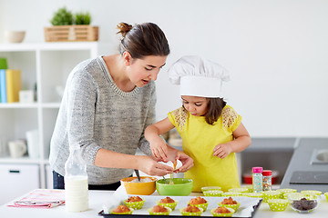 Image showing happy mother and daughter baking muffins at home