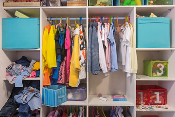 Image showing Open wardrobe with things and toys in the children\'s room