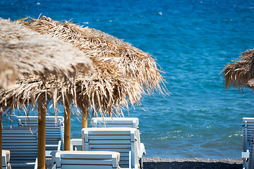 Image showing beach with umbrellas and deck chairs by the sea in Santorini