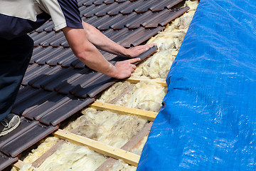 Image showing a roofer laying tile on the roof