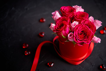 Image showing Pink roses bouquet packed in red box and placed on black stone background