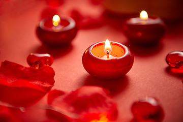 Image showing Romantic dinner decoration. Red candles, flower petals, on the t