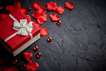 Image showing Gift box on black stone table. Romantic holiday background with rose petals