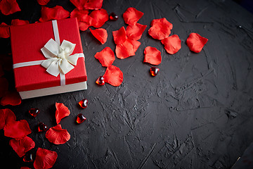 Image showing Gift box on black stone table. Romantic holiday background with rose petals