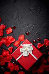 Image showing Gift box on black stone table. Romantic holiday background with rose petals