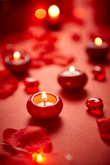 Image showing Romantic dinner decoration. Red candles, flower petals, on the table