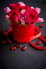 Image showing Pink roses bouquet packed in red box and placed on black stone background