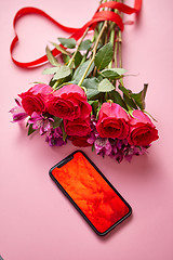 Image showing Pink roses bouquet with hart shaped bow and mobile phone with copy space screen