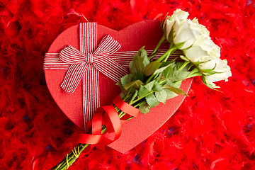 Image showing Heart shaped boxed gift, placed on red feathers background