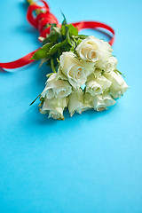 Image showing Bouquet of white roses with red bow on blue background