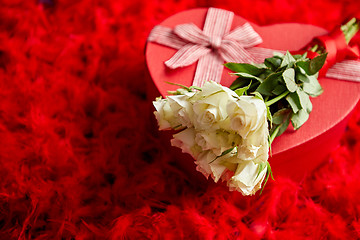 Image showing Heart shaped boxed gift, placed on red feathers background