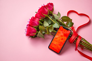 Image showing Pink roses bouquet with hart shaped bow and mobile phone with copy space screen