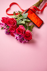 Image showing Pink roses bouquet with hart shaped bow and mobile phone with copy space screen