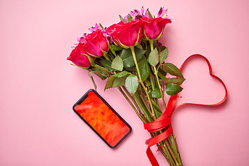 Image showing Pink roses bouquet with hart shaped bow and mobile phone with copy space screen