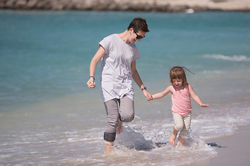 Image showing mother and daughter running on the beach