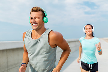 Image showing couple with headphones running outdoors