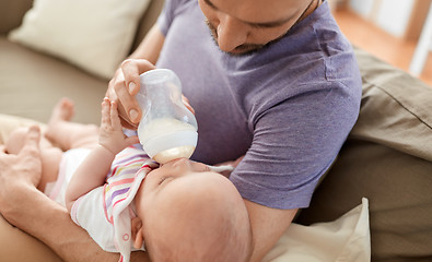 Image showing close up of father feeding baby from bottle