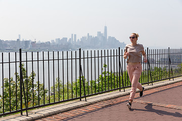 Image showing Healthy lifestyle. Woman is jogging on Hamilton ave by Hamilton park, New Jersey. Manhattan of New York City in the background.