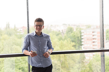 Image showing Businessman Standing In A Modern Building Near The Window With P