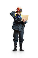 Image showing The studio shot of pensive senior bearded male miner standing at the camera with laptop on a white background.