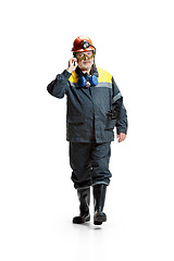 Image showing The studio shot of serious senior bearded male miner in motion at the camera with smartphone on a white background.