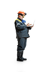 Image showing The studio shot of happy senior bearded male miner standing in profile view at the camera with laptop on a white background.