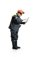 Image showing The studio shot of pensive senior bearded male miner standing in profile view at the camera with laptop on a white background.