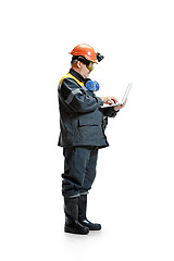 Image showing The studio shot of serious senior bearded male miner standing in profile view at the camera with laptop on a white background.