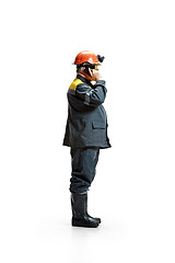 Image showing The studio shot of serious senior bearded male miner standing in profile view at the camera with smartphone on a white background.