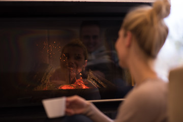 Image showing young woman drinking coffee in front of fireplace