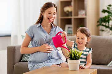 Image showing pregnant mother and daughter watering home plant