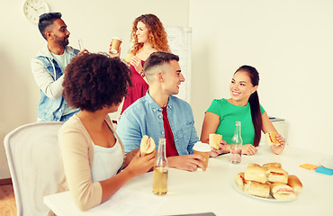 Image showing happy friends or team eating at office