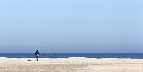 Image showing Old male photographer walking on the beach