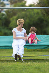 Image showing mother and little daughter swinging at backyard