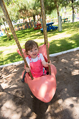 Image showing little girl swinging  on a playground